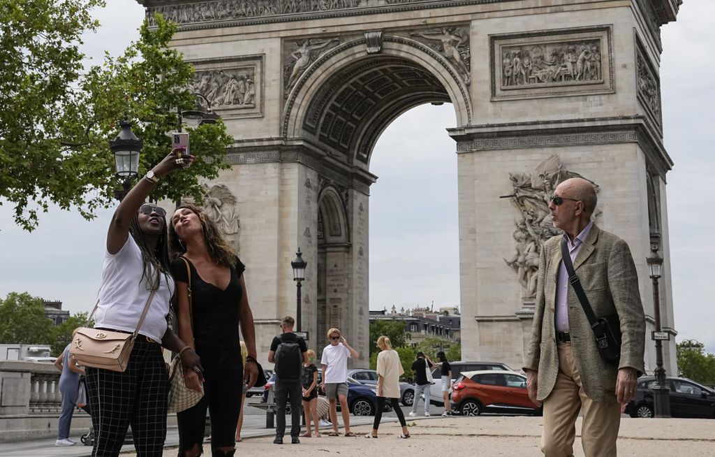 Zwei Frauen machen ein Selfie mit einem Smartphone vor dem dem Arc de Triomphe auf der Champs Elysees in Paris, Frankreich.