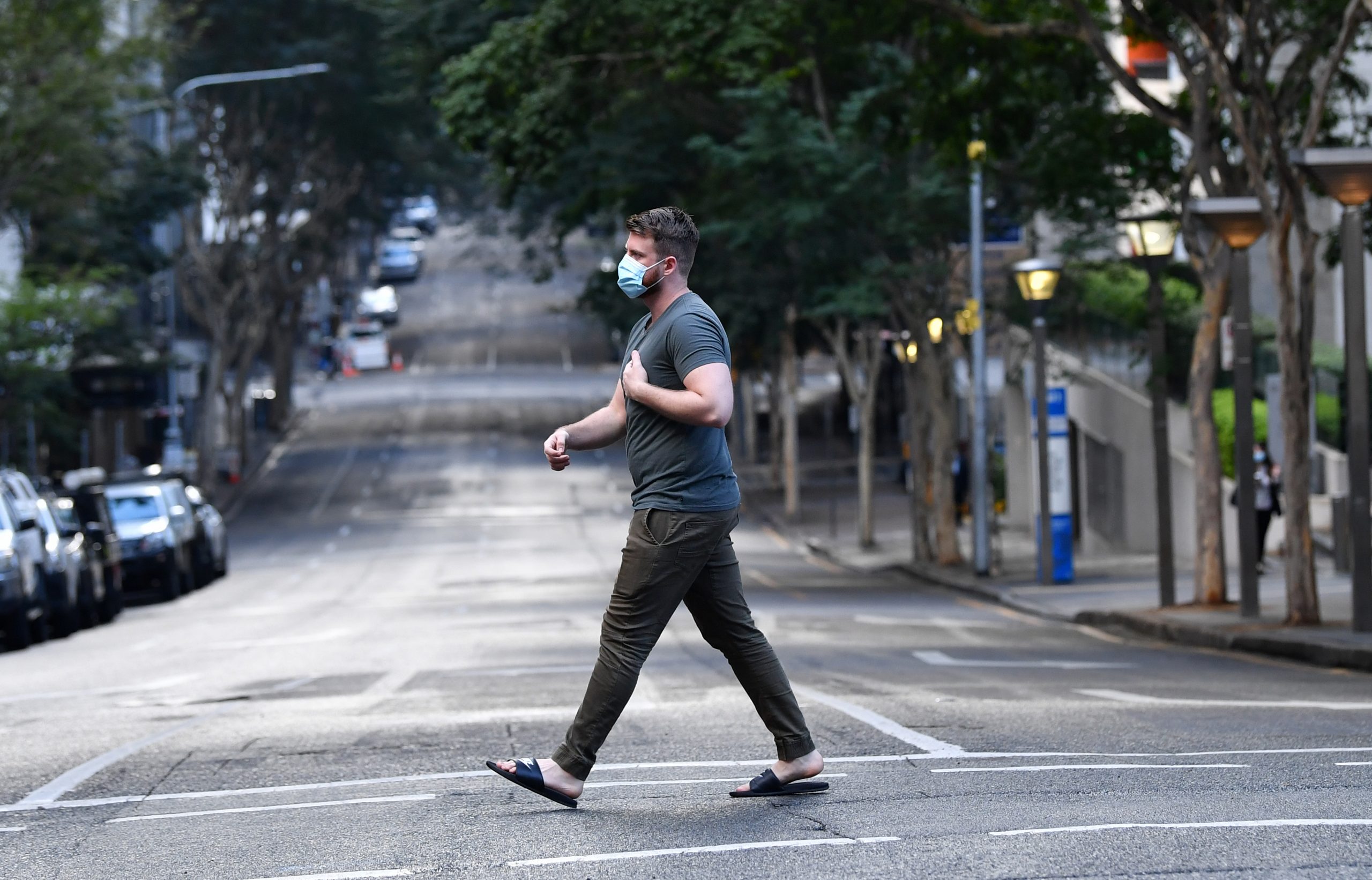 Ein Mann geht im australischen Brisbane mit Mund-Nasen-Schutz über die Straße