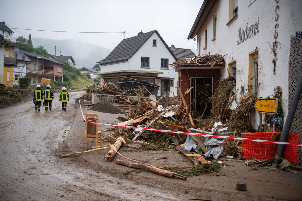 Einsatzkräfte der Feuerwehr gehen durch den verwüsteten Ortskern von Schuld in Rheinland-Pfalz.