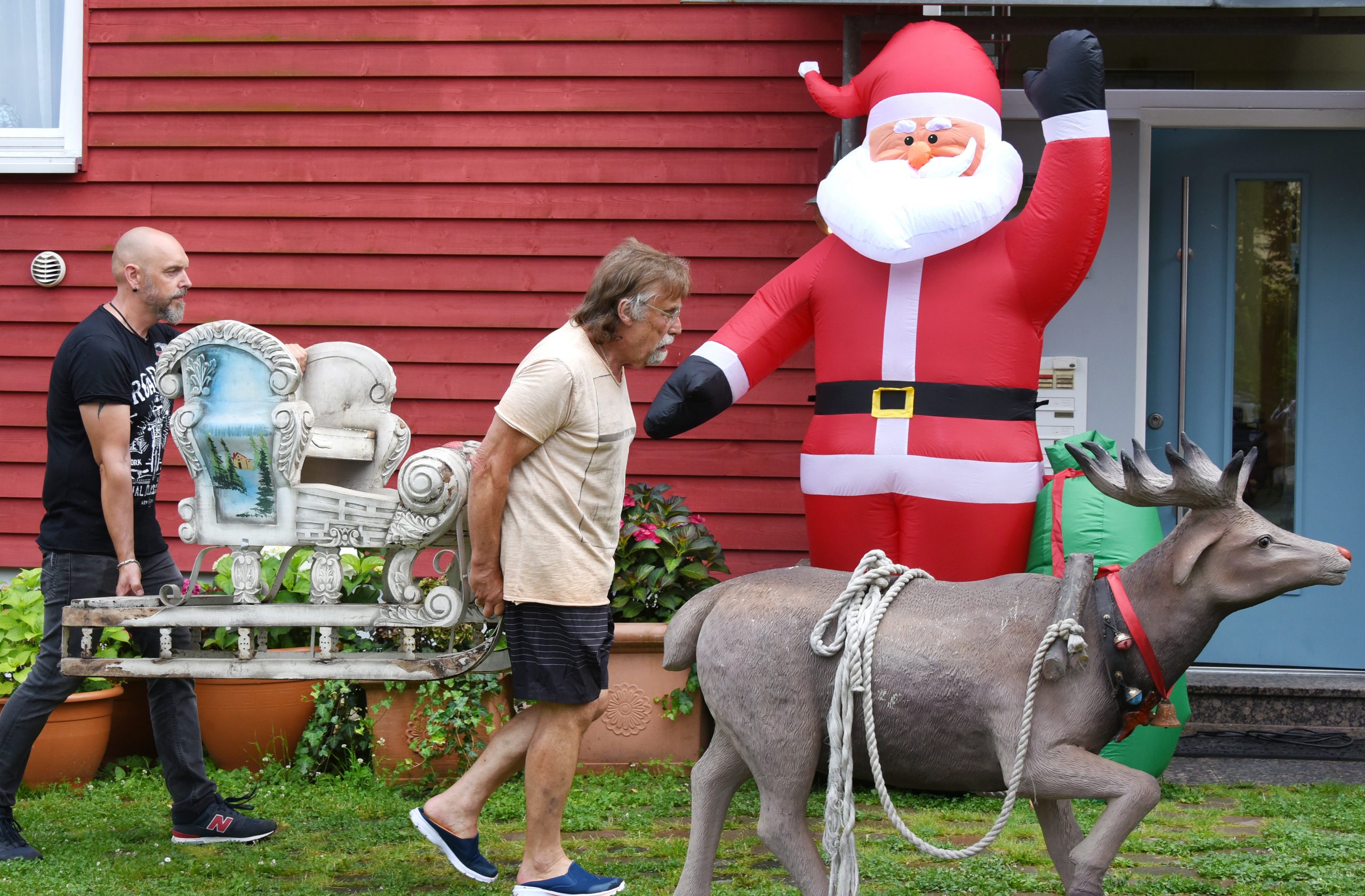 Dietmar Sawatzke und sein Sohn Sebastian tragen Weihnachtsdekoration vor den Eingang des Hauses.