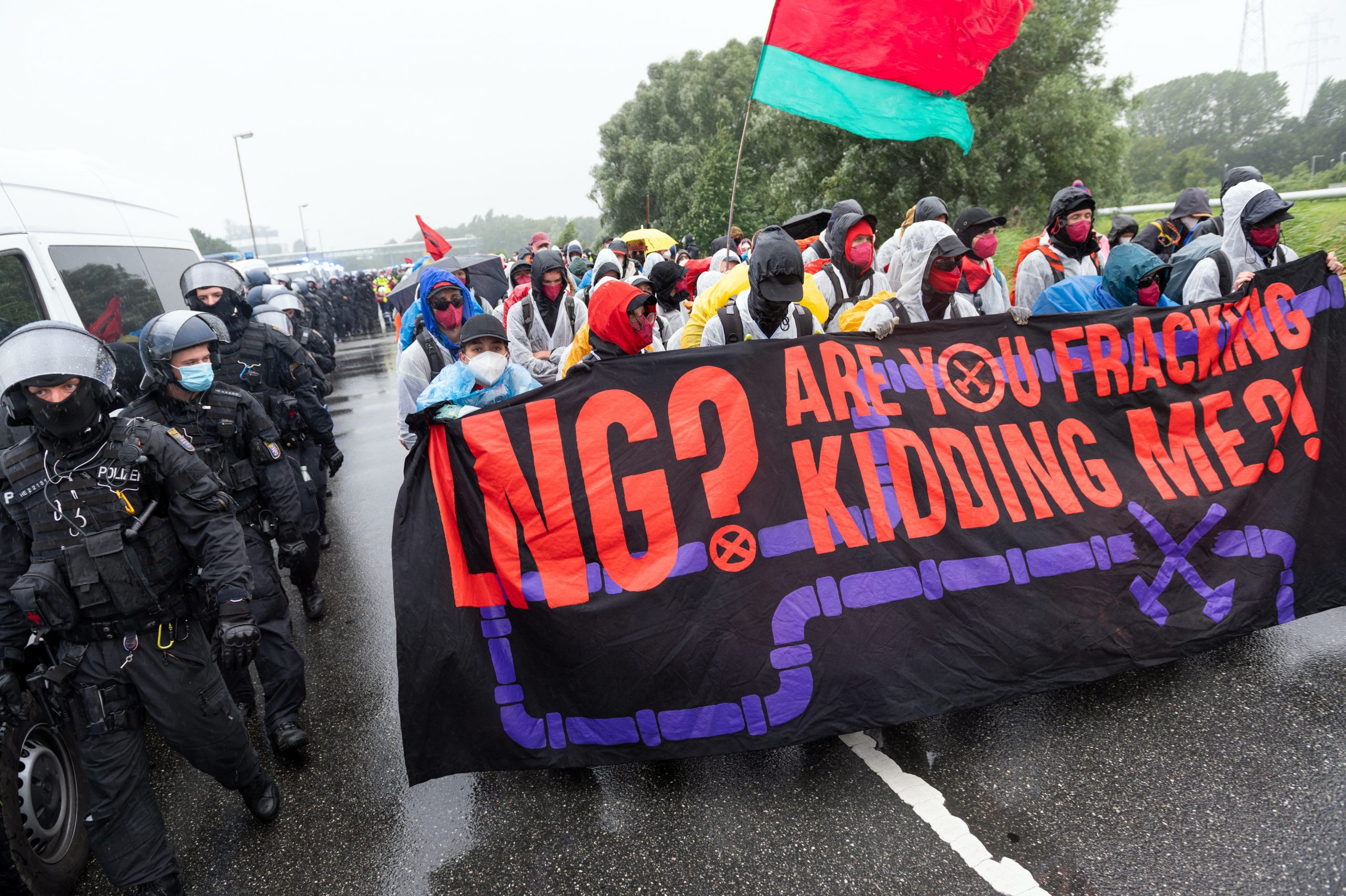 Aktivisten gehen, begleitet von der Polizei, mit einem Plakat mit der Aufschrift "LNG? Are you fracking kidding me?!".