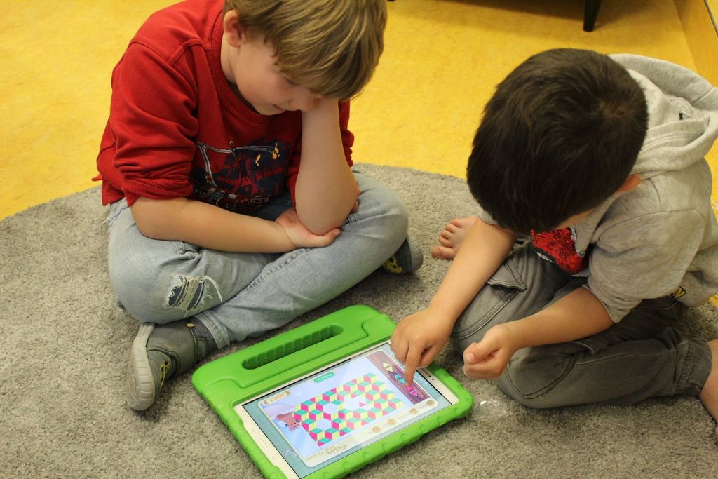 Kinder spielen an einem Tablet