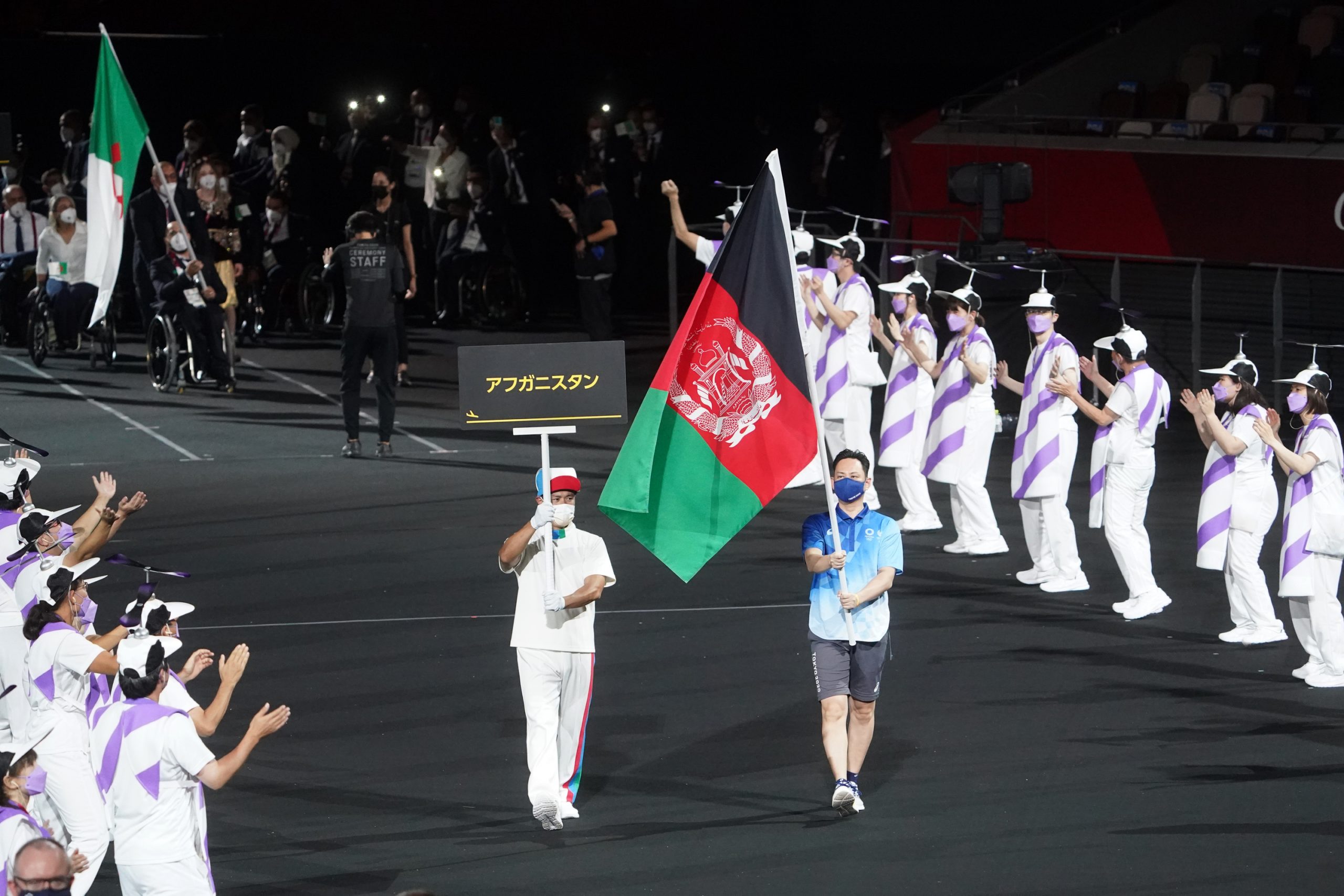 Ein Volunteer trägt beim Einmarsch der Paralympics in Tokio die afghanische Flagge