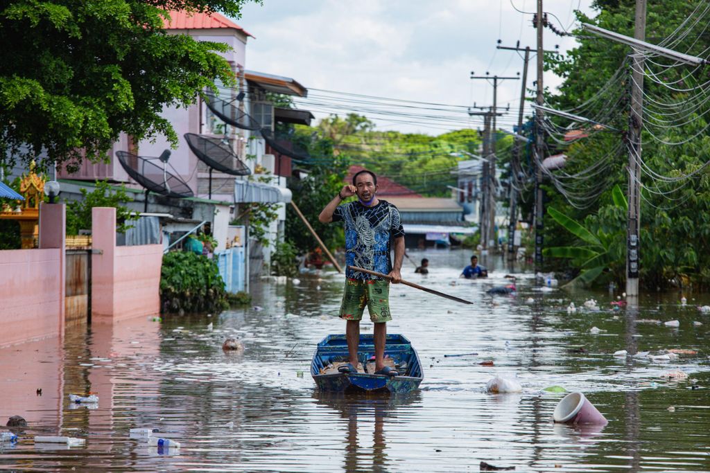Ein Bewohner steht auf einem Boot in einem überfluteten Dorf.