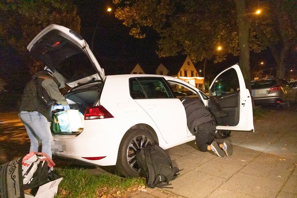 Polizeibeamte filzen einen weißen VW Golf.