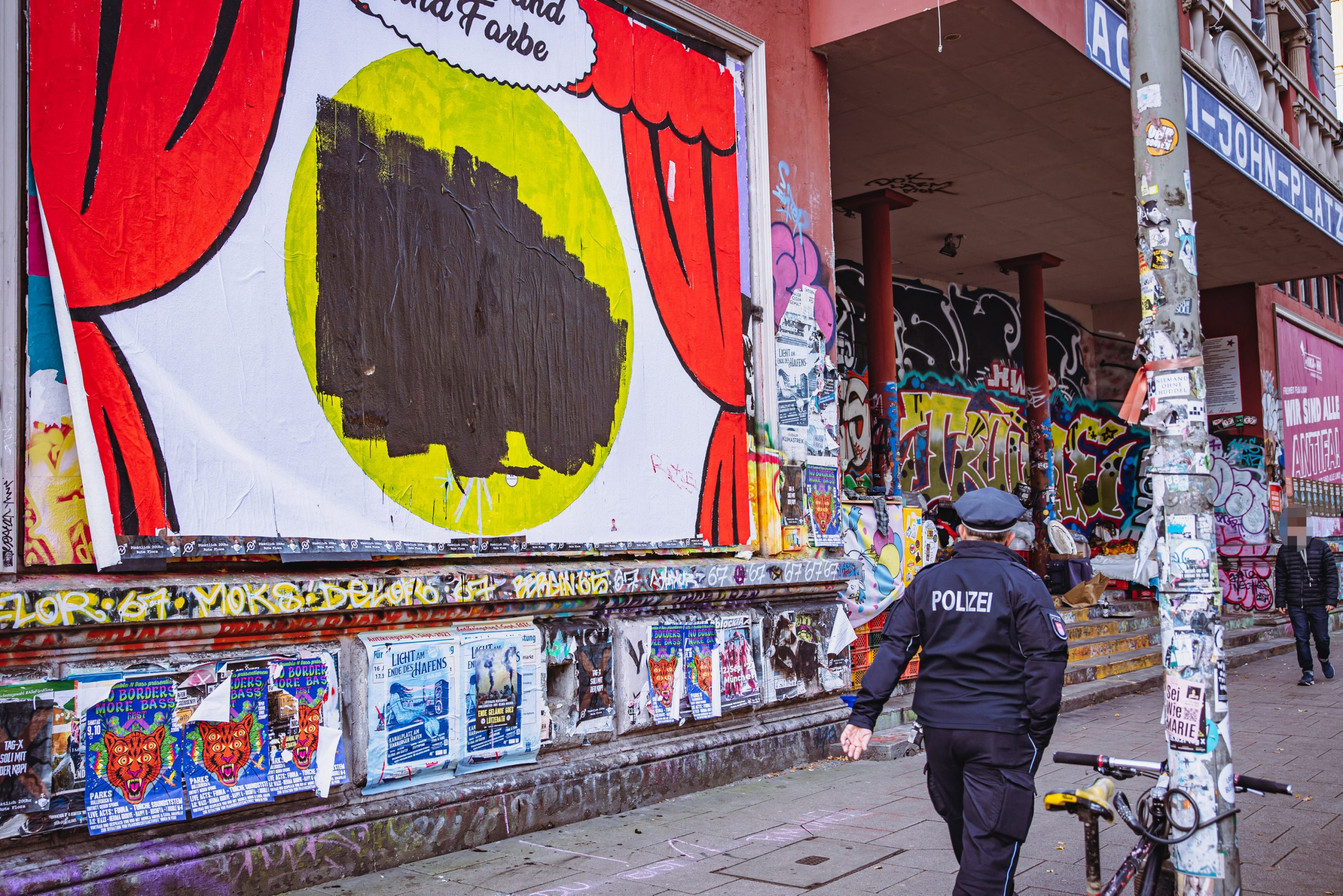 Eine Polizistin vor dem übermalten Plakat an der Roten Flora.