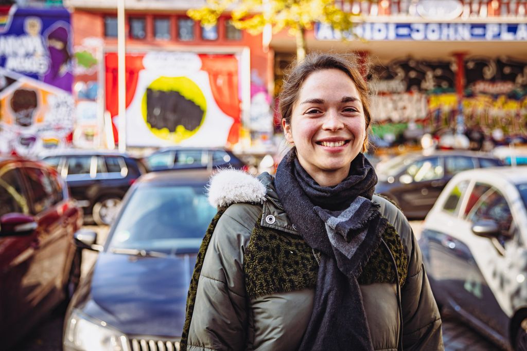 Luisa steht vor dem Plakat, dessen Aufschrift mit schwarzer Farbe übermalt ist