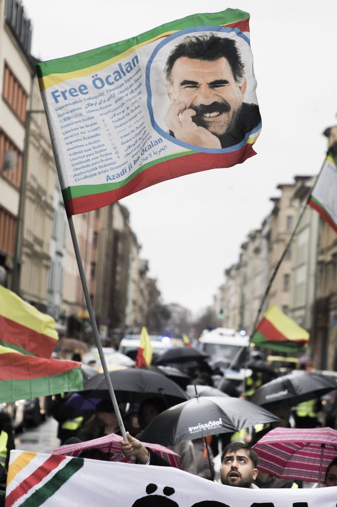 Menschen halten bei einer Demo eine Flagge mit dem Gesicht von Abdullah Öcalan hoch, dem PKK-Vorsitzenden.