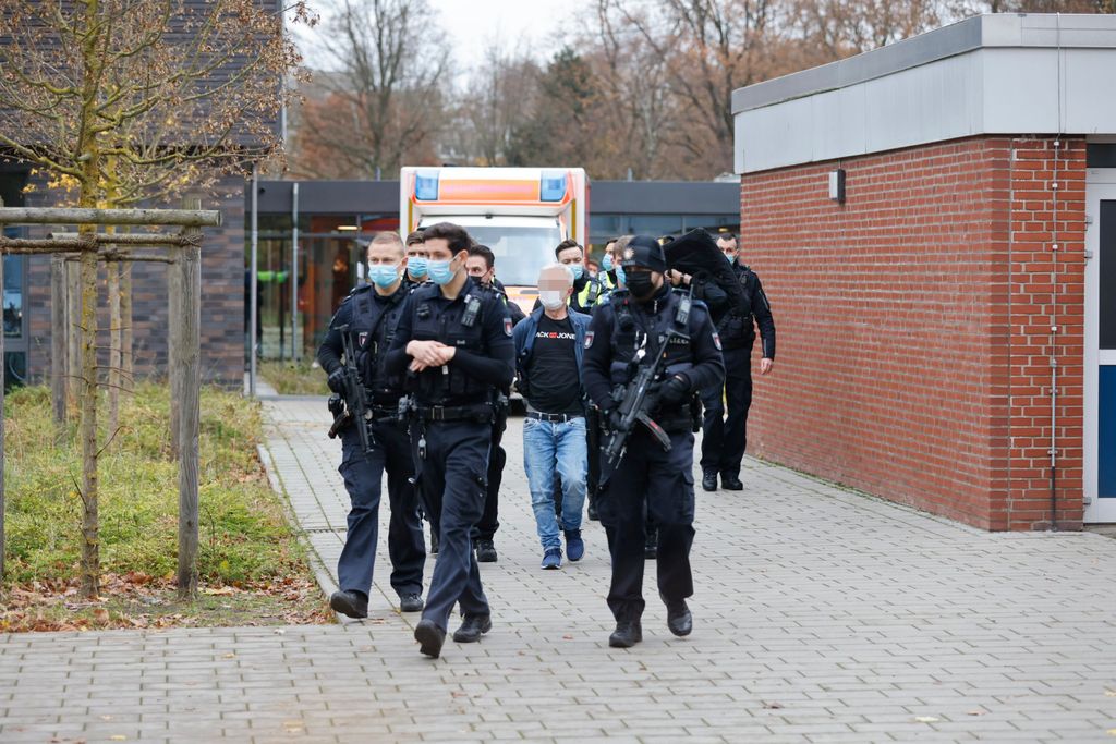 Polizisten führen den Verdächtigen ab.